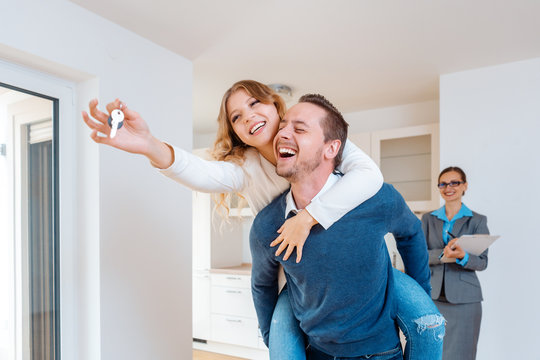 Man carrying his wife piggyback who is showing the house keys