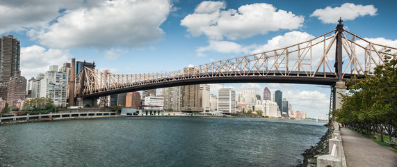Very large panoramic view on  Queensboro Bridge over East River, manhattan`s midtown skyscrapers and Roosevelt island