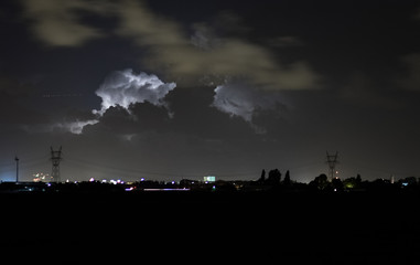 Naklejka na ściany i meble A thunderstorm between the cities of The Hague and Leiden, Holland is illuminated by intracloud lightning flashes