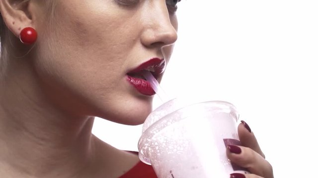 Slow motion close up of a pretty woman drinking milkshake through the straw