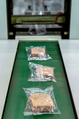 crispy wafer biscuits packing in the plastic back in production line on the conveyor belt of automatic packing machine at bakery factory. food industrial concept.