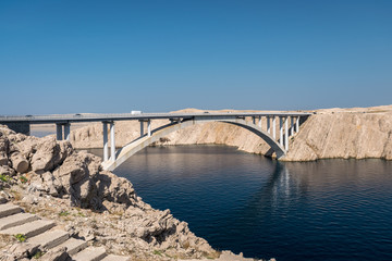 Deep blue water and rocky landscape with bridge which connects the Isle of Pag with the main land of Croatia