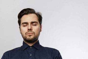 Handsome hispanic trendy man posing with closed eyes isolated on a white empty background.