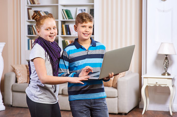 A young girl and boy child smiling and using laptop computer at home