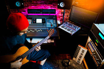 asian male musician recording acoustic guitar track in home studio