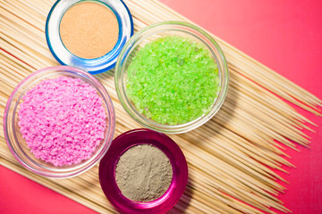 Naklejka premium Spa concept. Pink and green salt inside the glass. Blue and red clay. Top view. Space for your text.