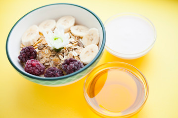 Fresh fruits, muesli and berries. Delicious and healthy breakfast on the yellow background. Space for a text. Top view.