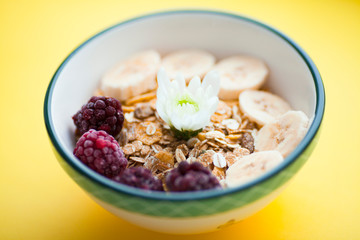 Fresh fruits, muesli and berries. Delicious and healthy breakfast on the yellow background. Space for a text. Top view.