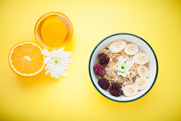 Fresh fruits, muesli and berries. Delicious and healthy breakfast on the yellow background. Space for a text. Top view.
