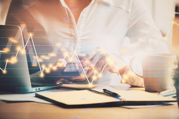 Hands typing on laptop. Business and Financial concept. Double exposure of stock market charts.