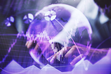 Hands typing on laptop. Business and Financial concept. Double exposure of stock market charts.