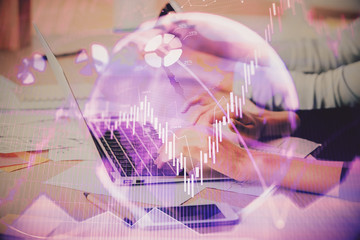 Hands typing on laptop. Business and Financial concept. Double exposure of stock market charts.