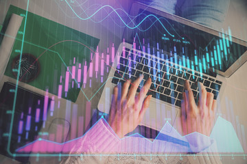 Hands typing on laptop. Business and Financial concept. Double exposure of stock market charts.