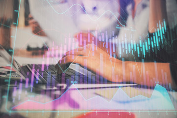 Hands typing on laptop. Business and Financial concept. Double exposure of stock market charts.