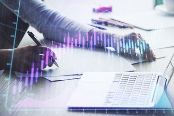 Close up of hands writing with double exposure of business charts. Financial concept.