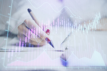 Close up of hands writing with double exposure of business charts. Financial concept.