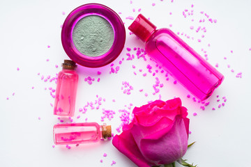 Naklejka premium Aromatherapy. Small glass bottles with cosmetic oils. Sea salt. Fresh pink rose. Ingredients for spa procedures on white background. Body care, skin care. Close up.