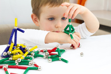 Cute little child boy playing magnets toy for brain development, fine motor skills and creativity concept