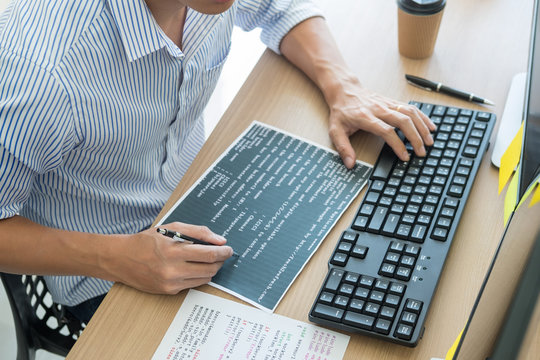 Serious busy hipster young web software developer programmer is coding or programming on a desktop computer information in modern office technologies Website design