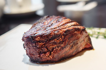 Closeup of delicious juicy meat steak on white plate in bright light, selective focus
