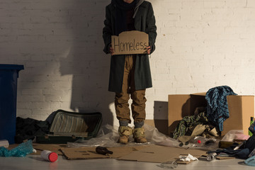 cropped view of houseless man holding piece of cardboard with "homeless" handwritten text