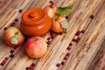 Fresh raw apples and clay pot with berries on the vintage wooden background. Autumn, healthy food, ingredients and holiday concept. Top view. Close up.