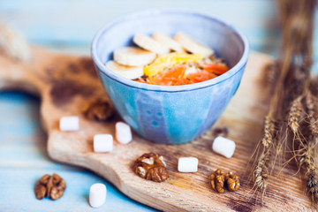 Muesli, sliced banana with nuts in the blue vintage bowl. Healthy food, diet, breakfast and snack concept. Lifestyle and flat lay. Top view. Close up.