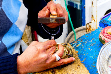 Man engraves a gold colored plate  on a tunisian market