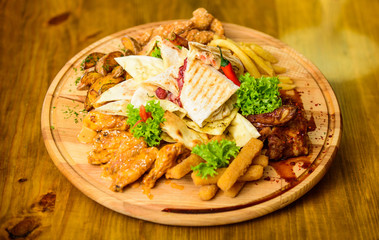 Pub menu snack. Tasty delicious snacks. Snack for beer. Restaurant food. Wooden board with lot french fries fish sticks burrito and meat steak served with salad. High calorie snack for group friends