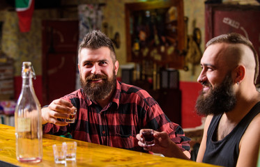 Strong alcohol drinks. Friends relaxing in pub. Men drinking alcohol together. Alcohol addiction. Hipster brutal man drinking alcohol with friend at bar counter. Men drunk relaxing at pub having fun