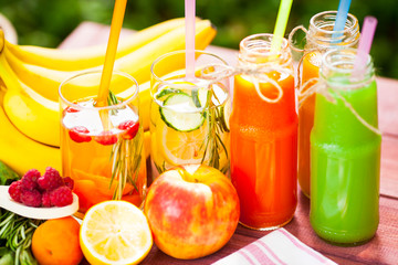 Fresh detox juices in glass bottles on the wooden background. Fruits and berries. Lifestyle, vegan food and drink, health care, diet and summer concept. Top view. Close up.