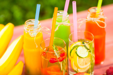 Fresh detox juices in glass bottles on the wooden background. Fruits and berries. Lifestyle, vegan food and drink, health care, diet and summer concept. Top view. Close up.