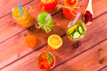 Fototapeta premium Fresh detox juices in glass bottles on the wooden background. Fruits and berries. Lifestyle, vegan food and drink, health care, diet and summer concept. Top view. Close up.