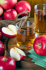 Apple juice in glasses and ripe red apples.