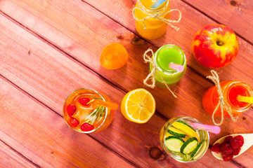 Fresh detox juices in glass bottles on the wooden background. Fruits and berries. Lifestyle, vegan food and drink, health care, diet and summer concept. Top view. Close up.