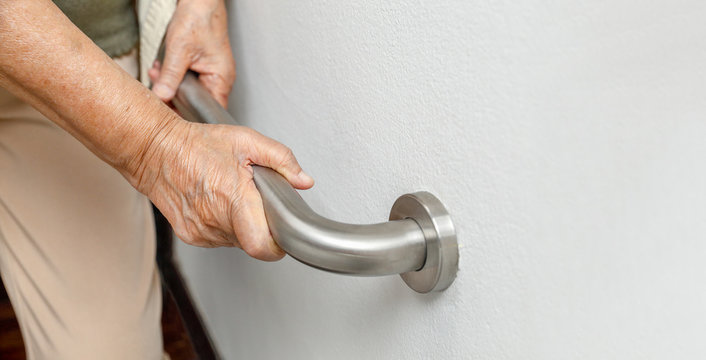 Elderly woman holding on handrail for safety walk steps