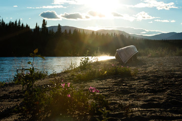 Canoe turned over on shore of Nisutlin River in boreal forest taiga wilderness of Yukon Territory,...