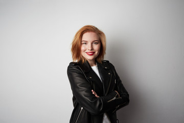 Cute redhead woman wearing black leather jacket over background. Copy paste space