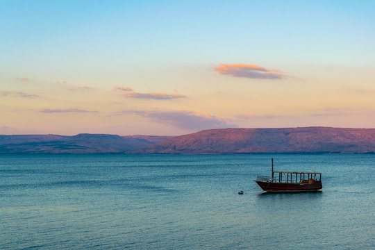 Sunset view of a wooden boat floating on the sea of galilee, Israel