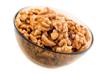 Studio photo of bowl with heap of peeled walnuts isolated on white