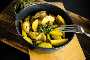 Baked potato wedges with rosemary on rustic background.