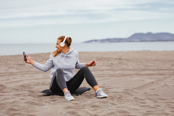 Young sports woman listens to music on the beach