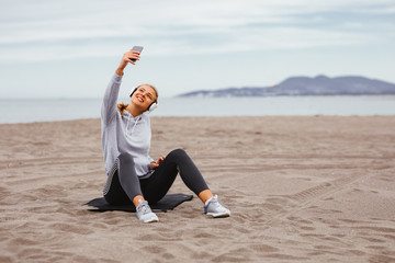 Young sports woman listens to music on the beach