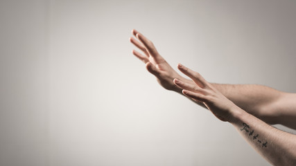 partial view of male hands with tattoo on grey background