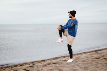 Young athletic man stretch out on the beach