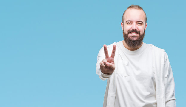 Young caucasian hipster man wearing sport clothes over isolated background smiling with happy face winking at the camera doing victory sign. Number two.