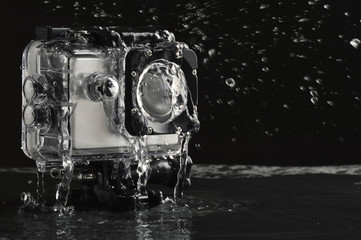 Flowing water on the waterproof action camera on wet black stone background 