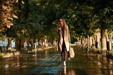Portrait of happy woman using mobile phone while walking through empty boulevard