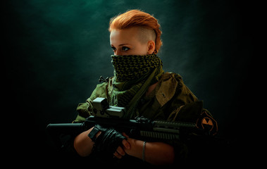 Woman with red hair with a bandage on his face, hold machine gun on her hands in darck room. Side view