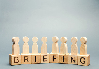 Wooden blocks with the word Briefing and a crowd of employees. Short press conference informative....
